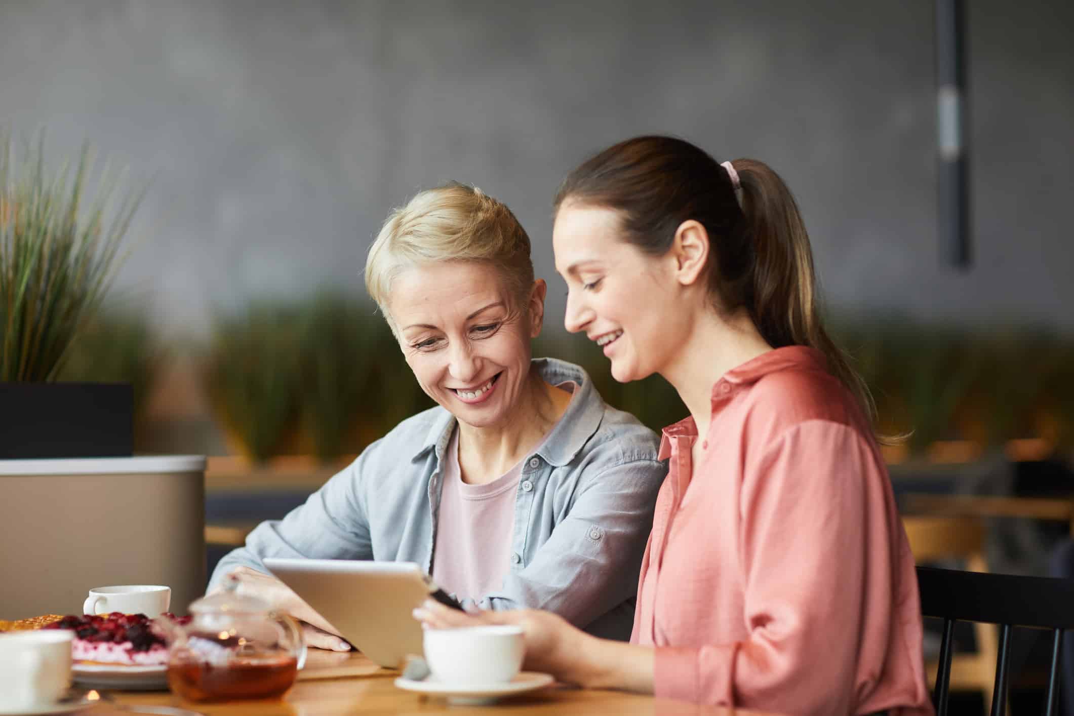 two women redeeming digital rewards on a tablet