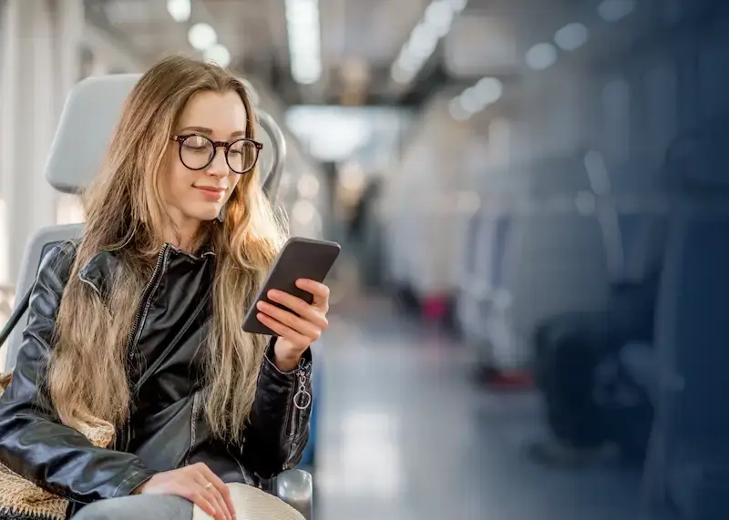 happy woman receiving a digital payout on her phone while riding the train.