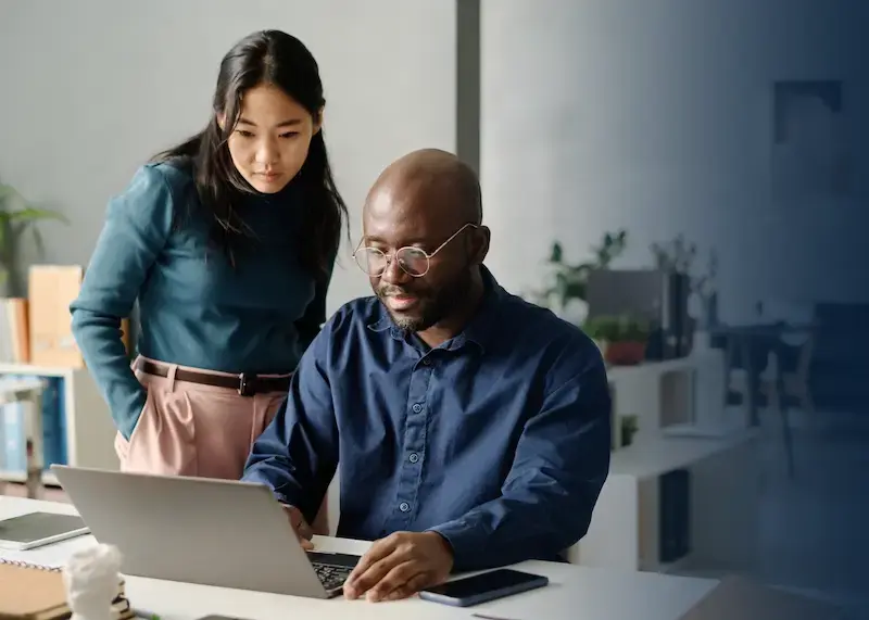 Two program managers using a laptop to access a gift card program.