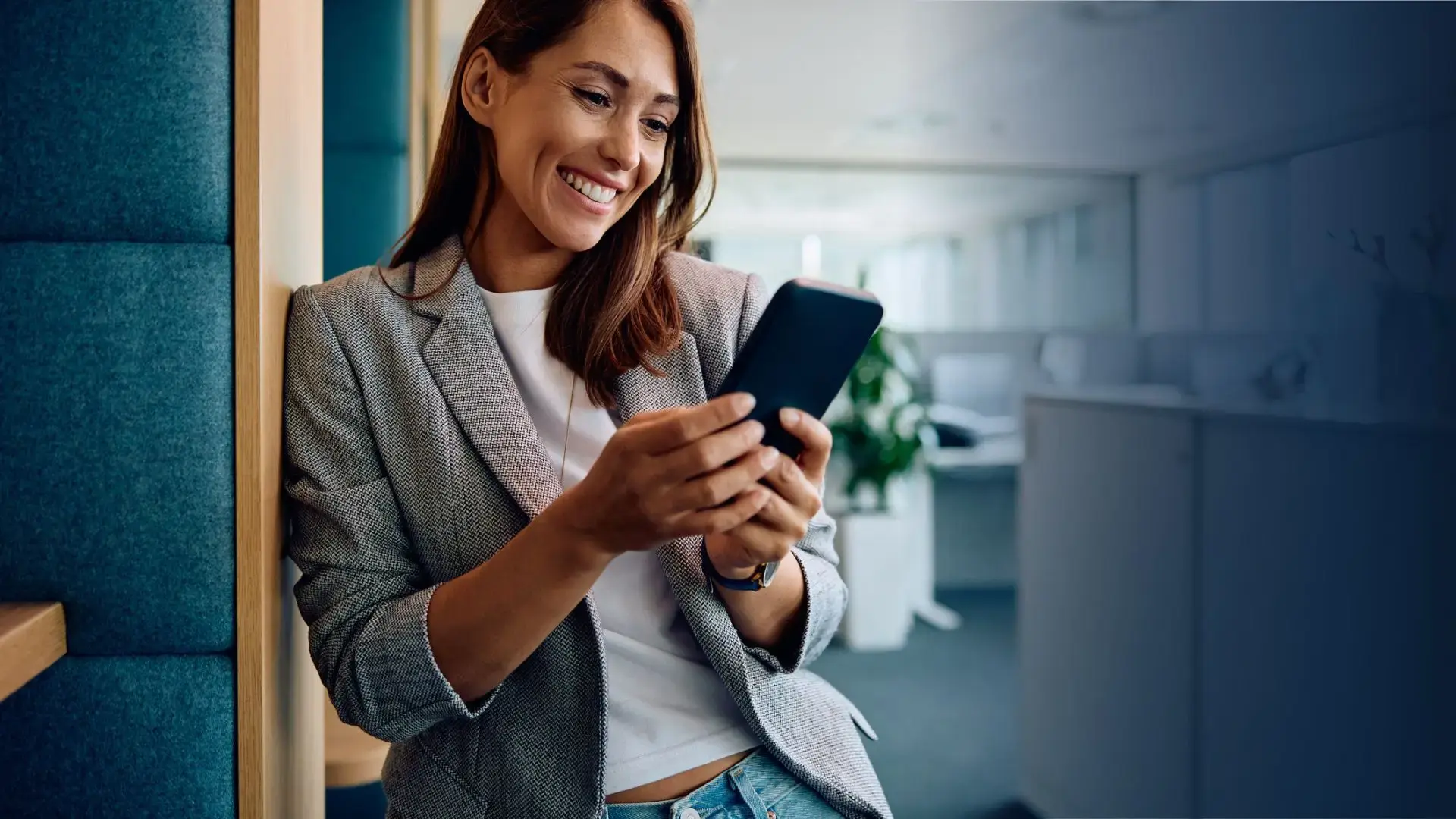 happy woman in office receiving a reward on her phone