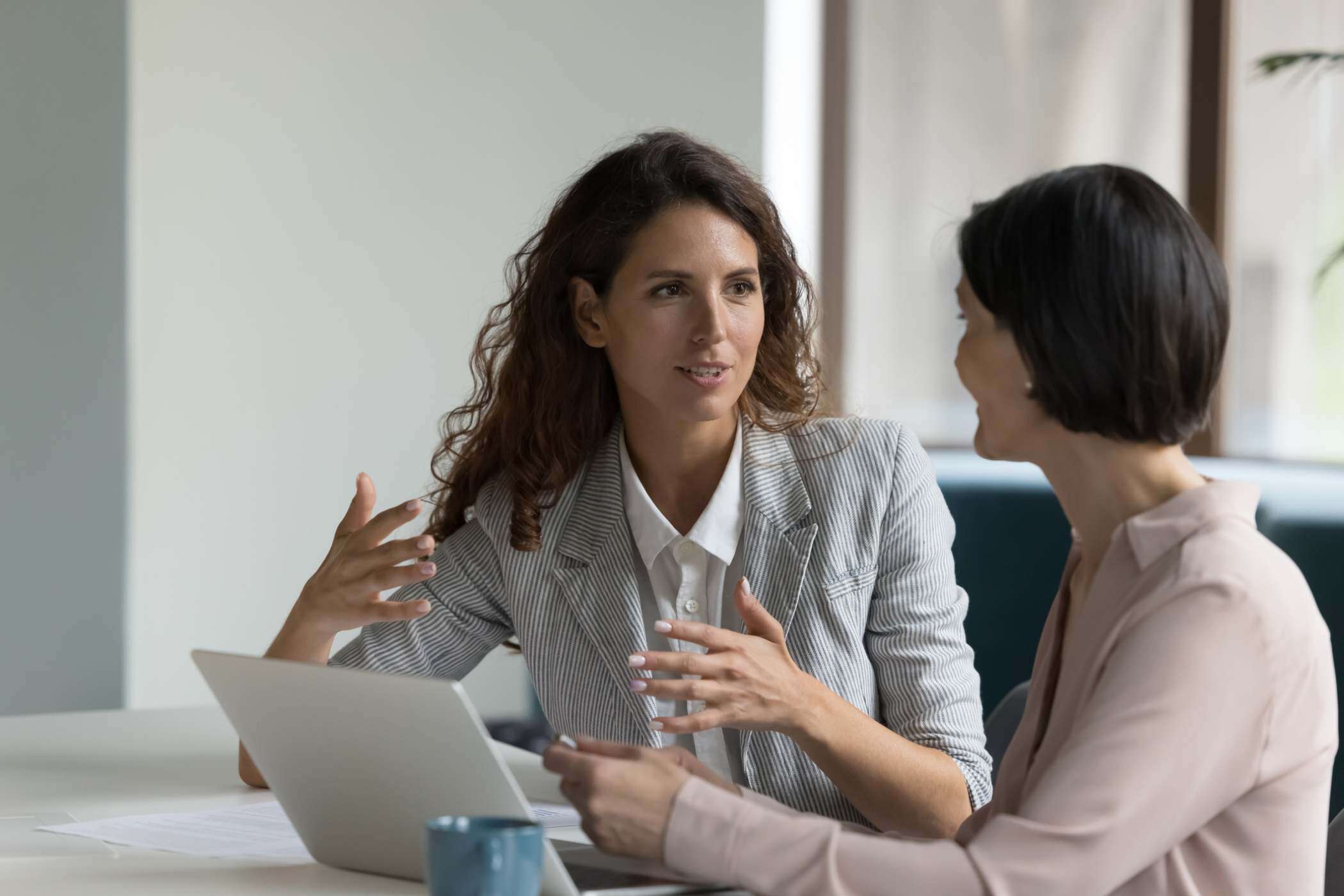 two program managers discussing their gift card company in front of a laptop